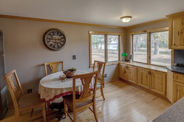 dining space with ornamental molding and light wood-type flooring