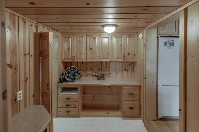 kitchen featuring wood walls, wooden ceiling, white refrigerator, and light brown cabinets