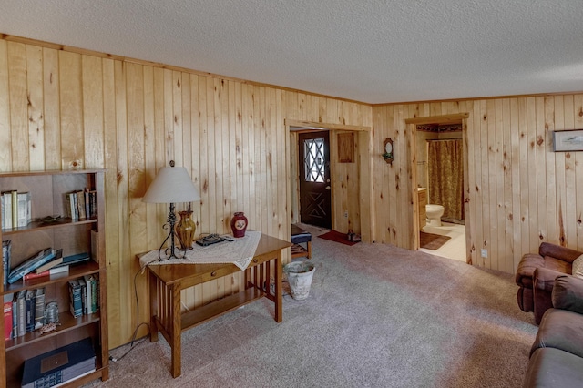 interior space featuring a textured ceiling, carpet flooring, and wood walls