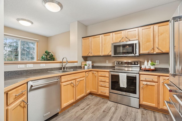 kitchen featuring light hardwood / wood-style floors, sink, light brown cabinets, a textured ceiling, and stainless steel appliances