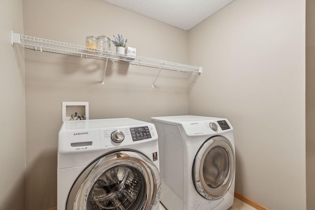 clothes washing area with separate washer and dryer and a textured ceiling