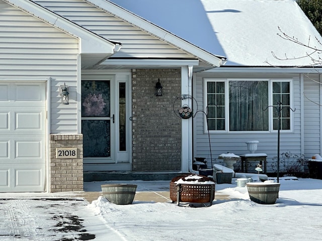 snow covered property entrance with a garage