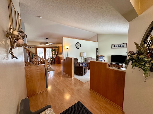 interior space featuring lofted ceiling, a textured ceiling, ceiling fan, and light hardwood / wood-style flooring