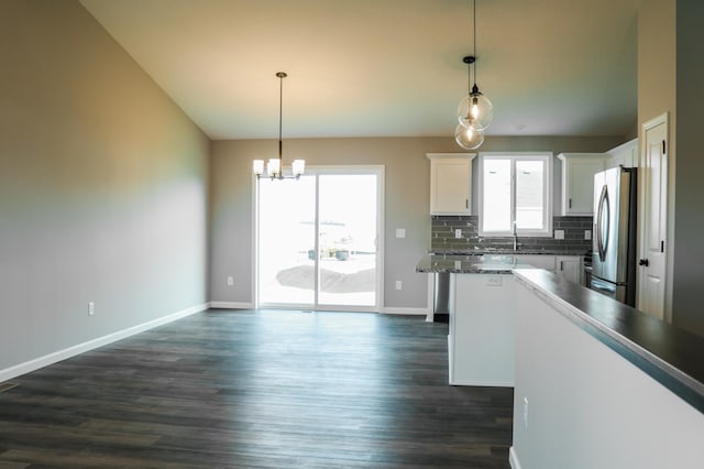 kitchen featuring white cabinetry, stainless steel refrigerator, pendant lighting, and tasteful backsplash