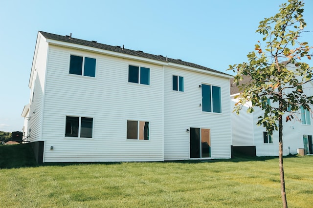 rear view of property featuring central air condition unit and a yard