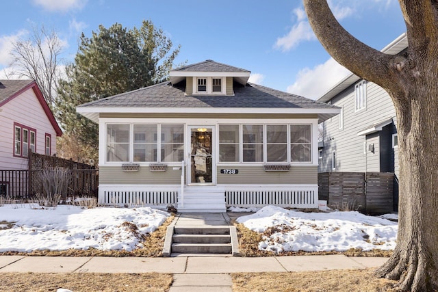 bungalow featuring a sunroom, roof with shingles, and fence