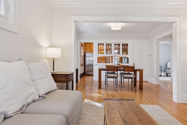 living room featuring baseboards, light wood-style flooring, and crown molding