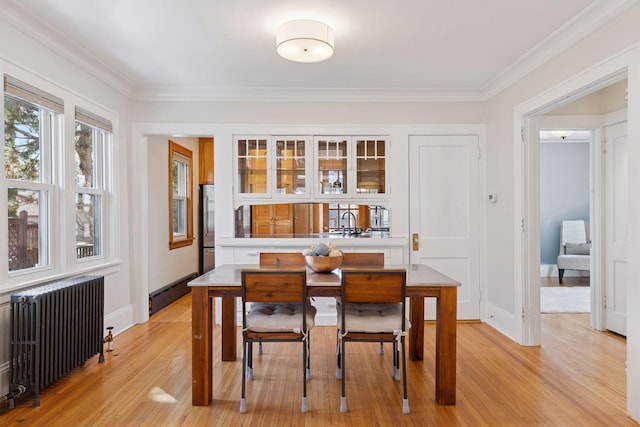 dining room featuring a baseboard radiator, light wood-type flooring, radiator heating unit, and crown molding