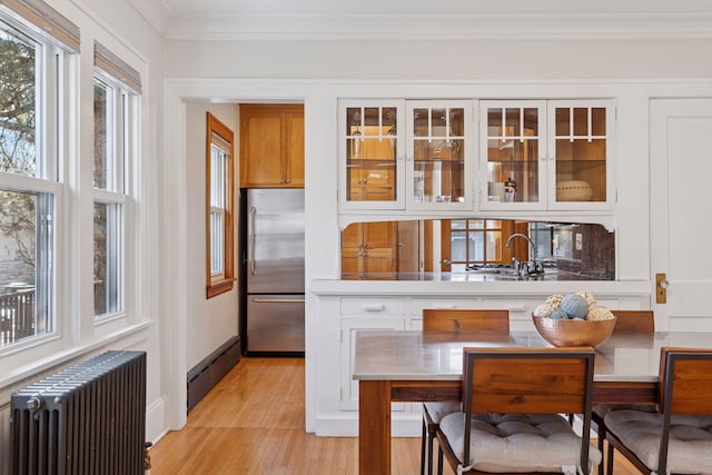 interior space featuring crown molding, stainless steel built in refrigerator, radiator heating unit, baseboard heating, and a sink