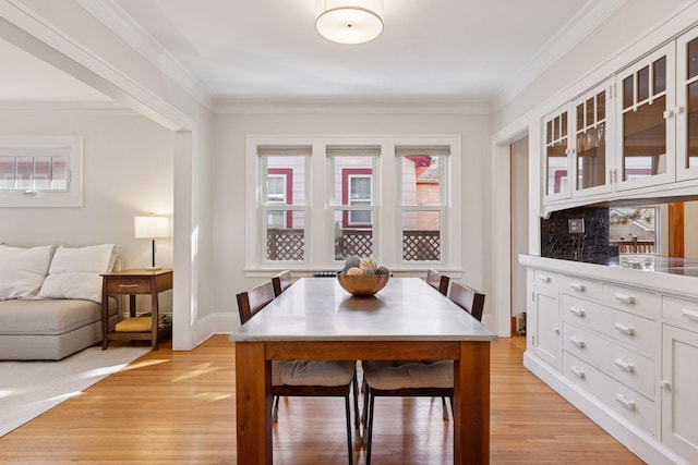 dining area featuring crown molding, baseboards, and light wood-type flooring