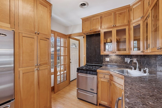 kitchen featuring visible vents, light wood-style flooring, a sink, appliances with stainless steel finishes, and backsplash