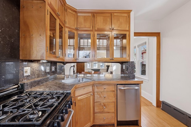 kitchen featuring a sink, glass insert cabinets, baseboard heating, and appliances with stainless steel finishes