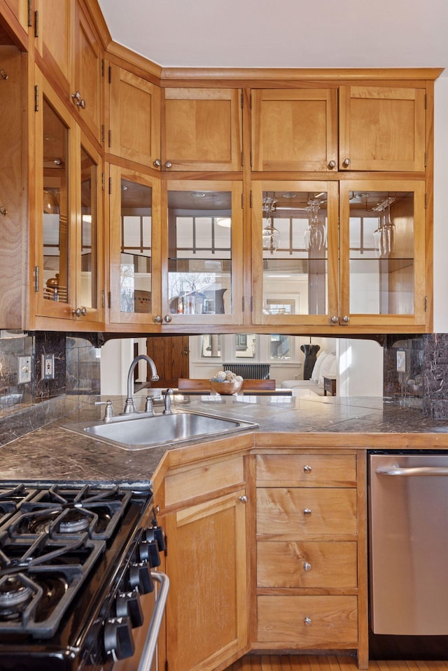 kitchen with a sink, stainless steel appliances, glass insert cabinets, and decorative backsplash