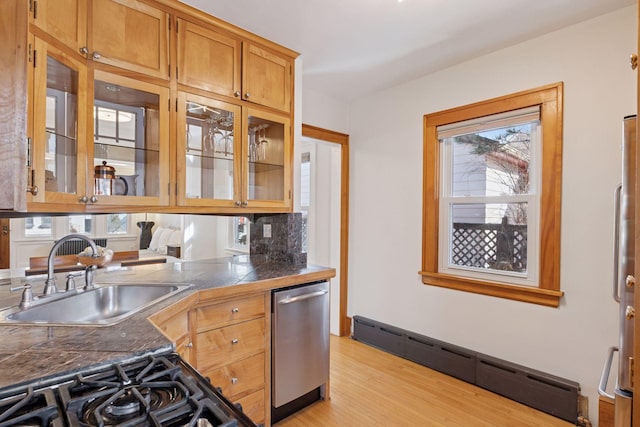 kitchen featuring a sink, glass insert cabinets, a baseboard heating unit, light wood-type flooring, and stainless steel dishwasher