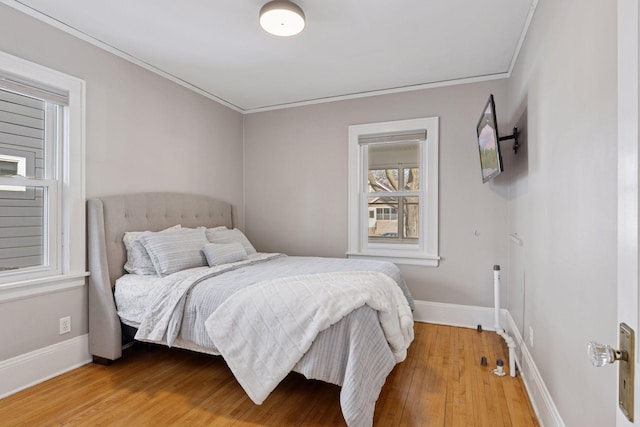 bedroom featuring baseboards, wood-type flooring, and crown molding