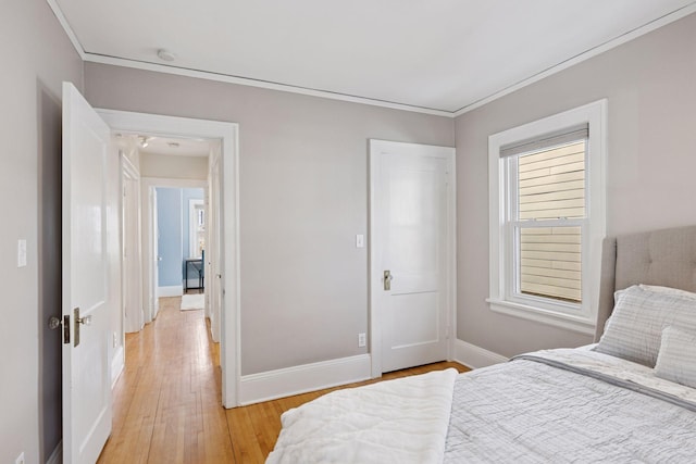 bedroom with light wood-style flooring, crown molding, and baseboards