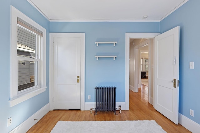 interior space featuring baseboards, wood finished floors, radiator heating unit, and crown molding