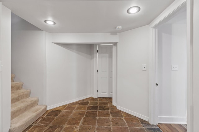 finished below grade area featuring stairs, stone finish flooring, and baseboards