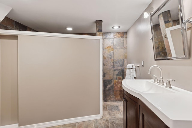 full bath featuring stone finish floor, recessed lighting, vanity, and walk in shower