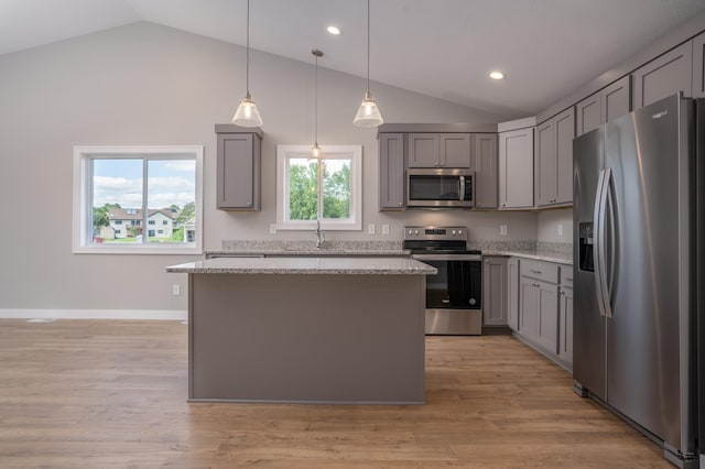 kitchen featuring decorative light fixtures, gray cabinets, a center island, light wood-type flooring, and stainless steel appliances