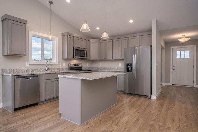 kitchen featuring light stone countertops, appliances with stainless steel finishes, a center island, hanging light fixtures, and gray cabinetry