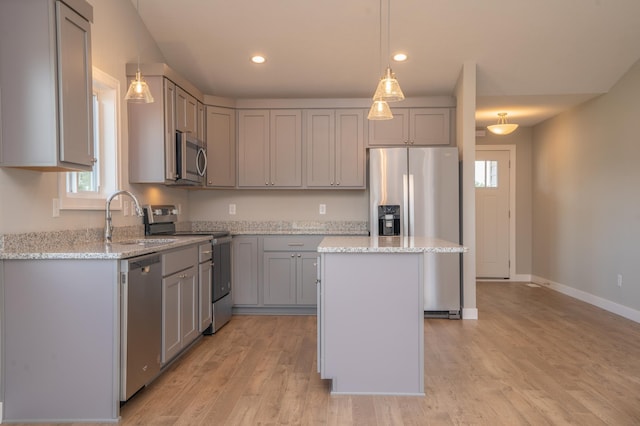 kitchen with light stone countertops, appliances with stainless steel finishes, gray cabinets, and a kitchen island