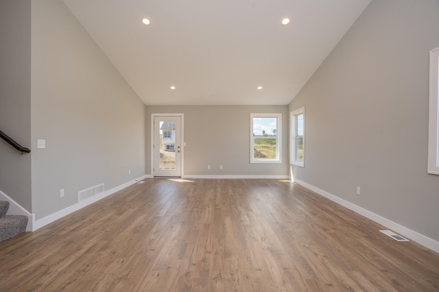 unfurnished living room with vaulted ceiling and light wood-type flooring