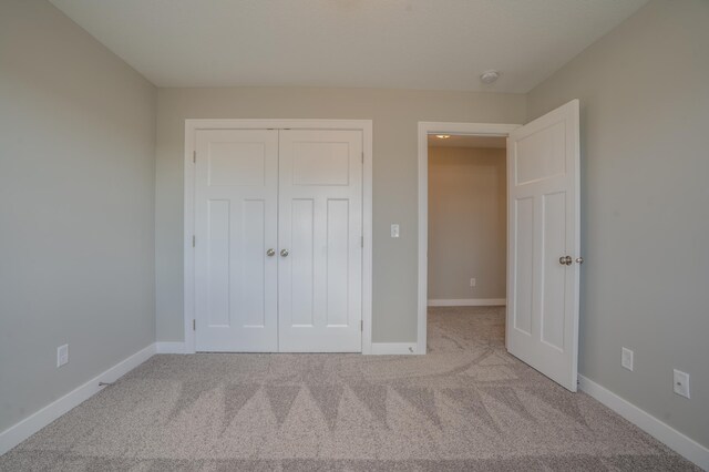 unfurnished bedroom with a closet and light colored carpet