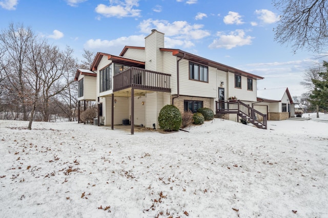 snow covered rear of property featuring a wooden deck