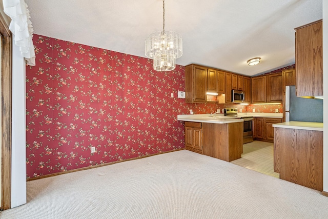 kitchen featuring pendant lighting, stainless steel appliances, vaulted ceiling, kitchen peninsula, and a chandelier