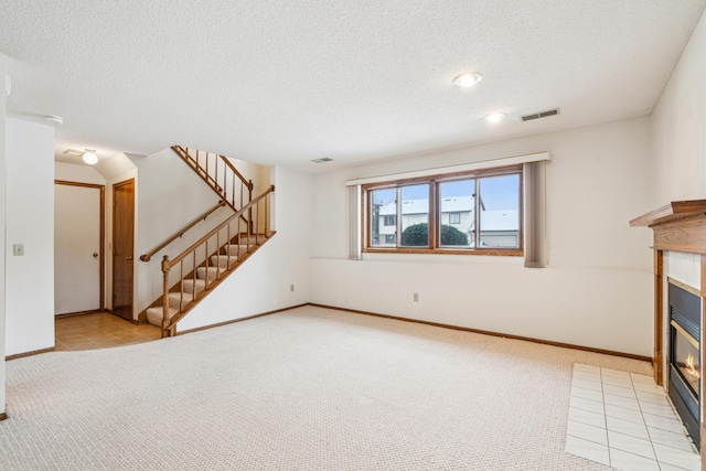 unfurnished living room with light colored carpet and a textured ceiling