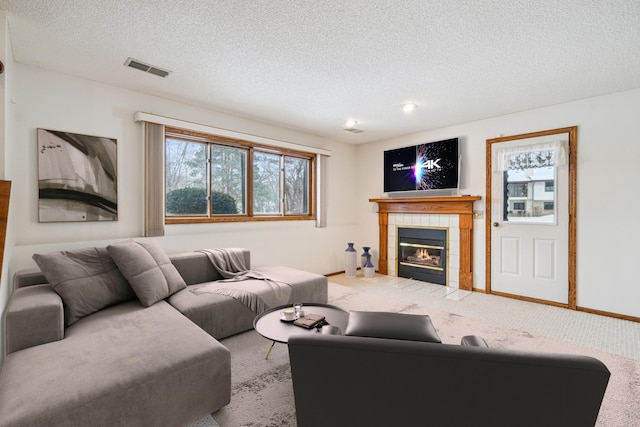 carpeted living area featuring visible vents, plenty of natural light, a textured ceiling, and a tiled fireplace