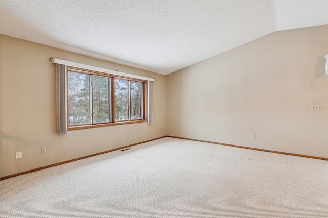 carpeted empty room featuring a textured ceiling, vaulted ceiling, visible vents, and baseboards