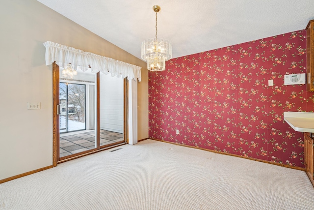 carpeted spare room featuring wallpapered walls, an inviting chandelier, and baseboards