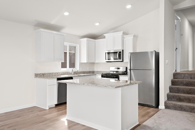 kitchen with light hardwood / wood-style floors, white cabinetry, appliances with stainless steel finishes, and a center island