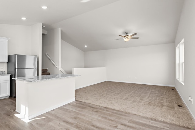 kitchen featuring ceiling fan, light stone countertops, white cabinetry, and lofted ceiling