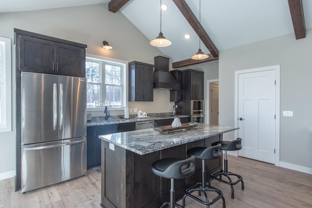 kitchen with premium range hood, a center island, hanging light fixtures, light stone countertops, and appliances with stainless steel finishes