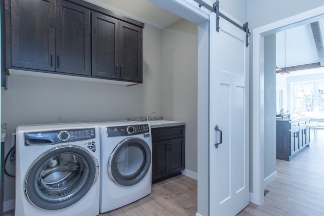 washroom featuring light hardwood / wood-style floors, a barn door, independent washer and dryer, cabinets, and sink