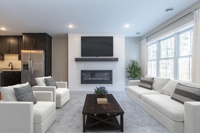 carpeted living room with sink and a large fireplace