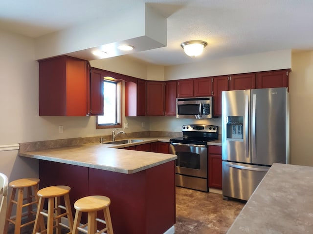 kitchen with kitchen peninsula, appliances with stainless steel finishes, sink, and a kitchen bar