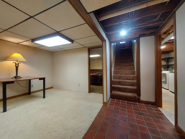 basement with dark carpet, a paneled ceiling, and washing machine and clothes dryer