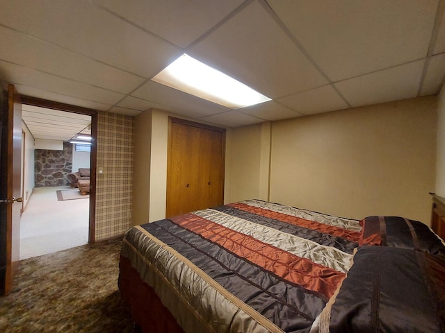 carpeted bedroom featuring a paneled ceiling and a closet