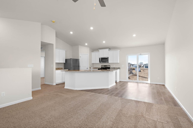 kitchen with light carpet, white cabinetry, an island with sink, ceiling fan, and appliances with stainless steel finishes