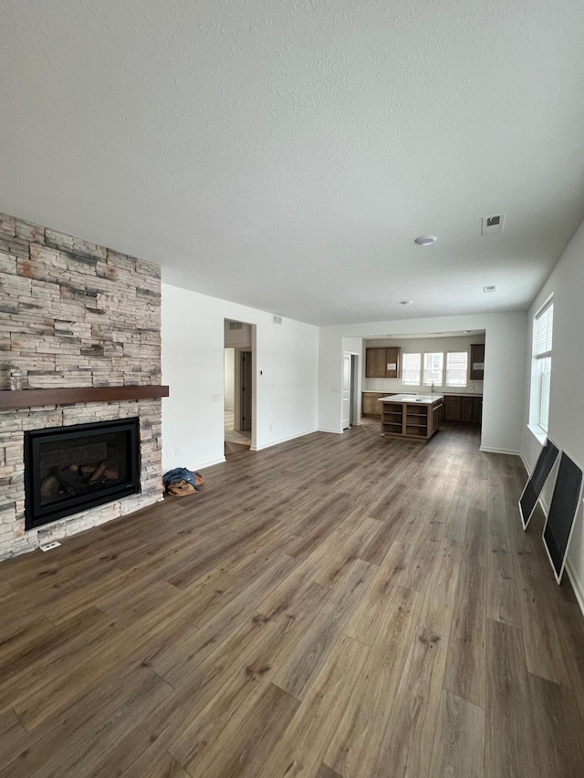 unfurnished living room with hardwood / wood-style flooring, a textured ceiling, and a fireplace