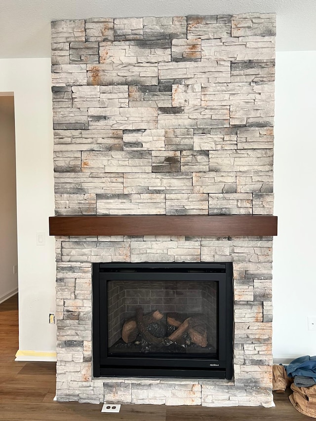 interior details featuring wood-type flooring and a stone fireplace