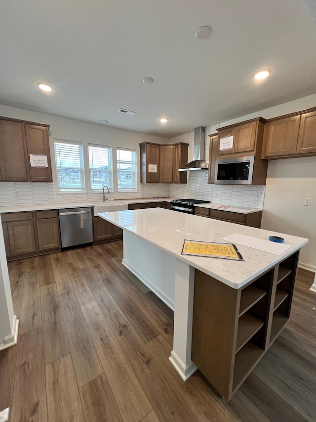 kitchen with stainless steel dishwasher, built in microwave, wall chimney exhaust hood, and a kitchen island