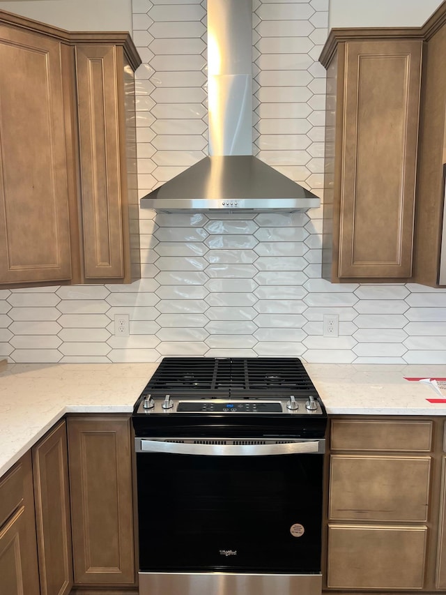 kitchen featuring light stone countertops, decorative backsplash, stainless steel range with gas cooktop, and wall chimney range hood