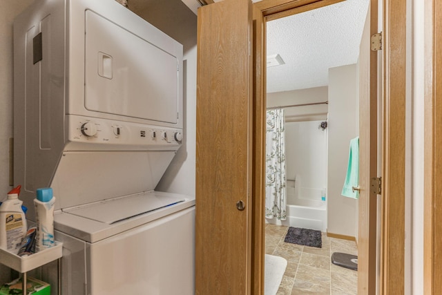 clothes washing area featuring stacked washing maching and dryer and a textured ceiling