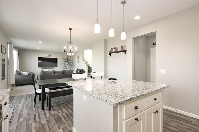 kitchen featuring light stone counters, decorative light fixtures, recessed lighting, dark wood-type flooring, and a kitchen island