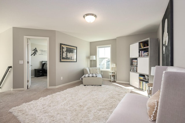 sitting room with an upstairs landing, baseboards, and light colored carpet